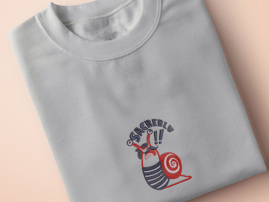 An Embroidered light grey t-shirt design of a cute chib french snail with the quote sacreblu!