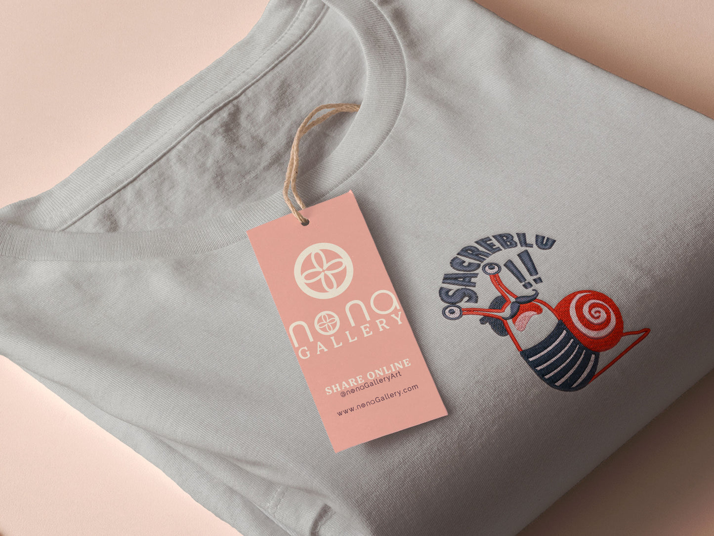 An Embroidered light grey t-shirt design of a cute chib french snail with the quote sacreblu!