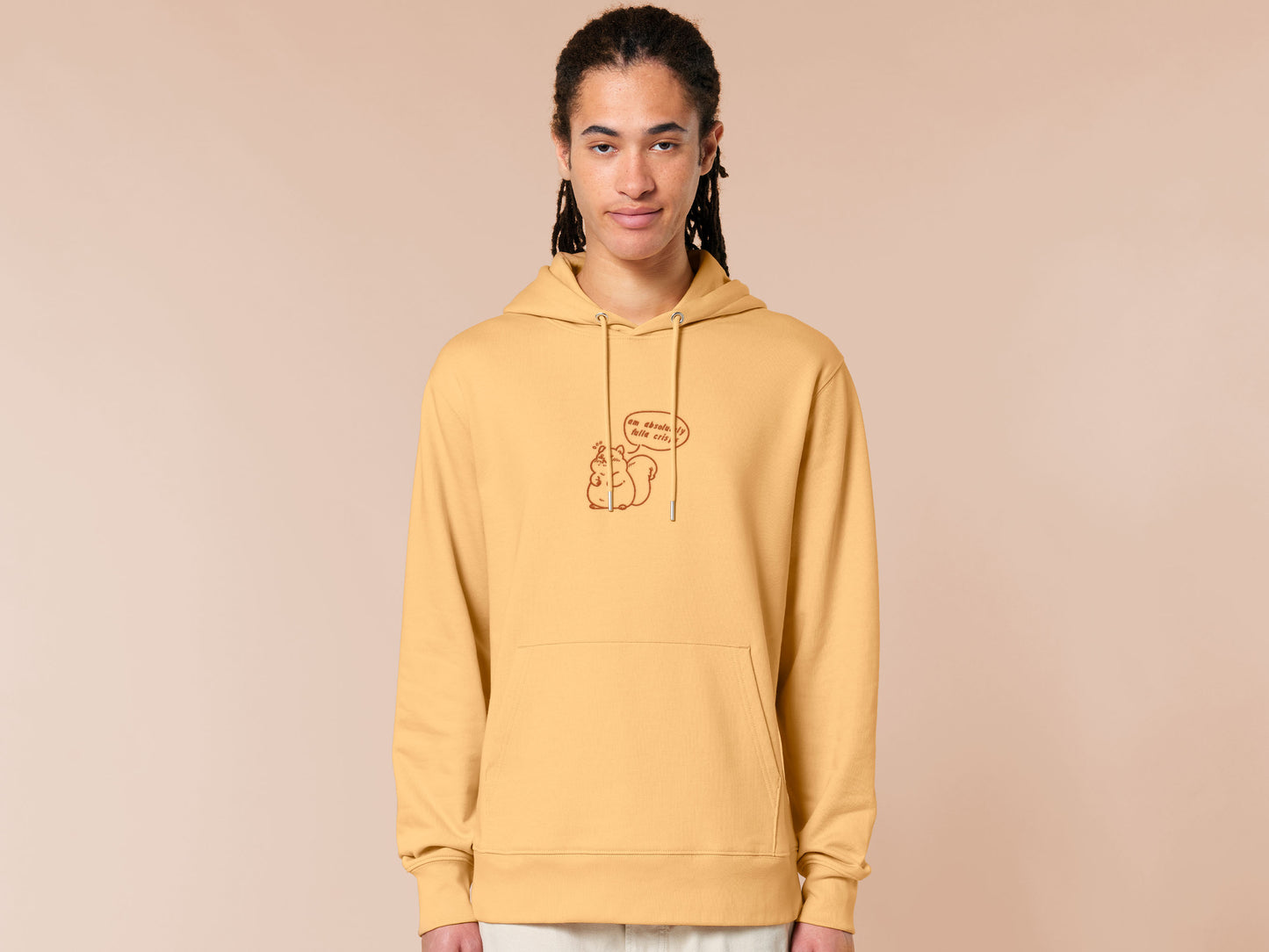 A man wearing a long sleeved yellow fleece hoodie with an embroidered design of a cute fat squirrel and a speech bubble with the text am absolutely fulla crisps