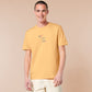 A yellow t-shirt with a blue and pink embroidered design of a cute smiling dinosaur looking at a meteor plummeting to earth with the text uh oh...