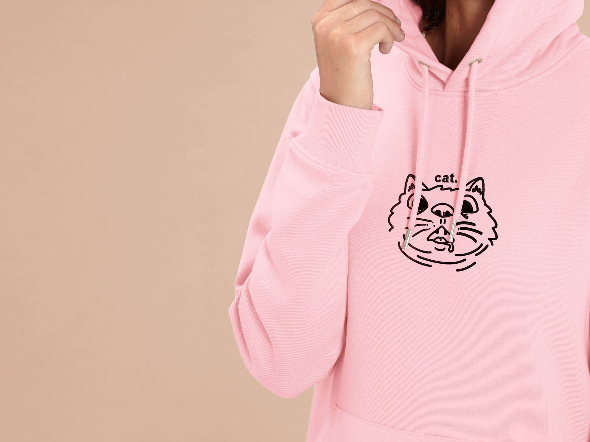 Woman wearing a long sleeved pink fleece hoodie with an Embroidered cat design