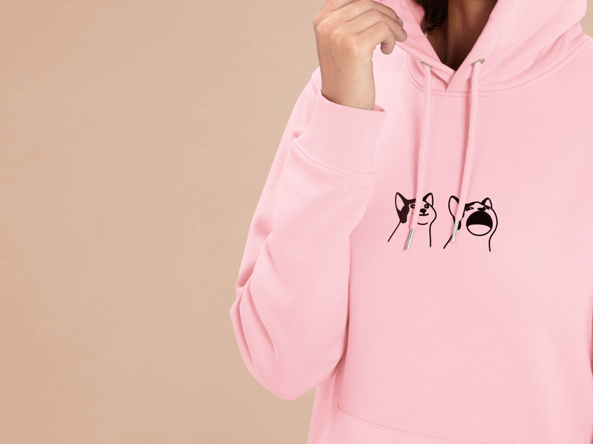 A woman wearing a pink long sleeved fleece hoodie, with an embroidered brown thread design of a cute popcat the cat meme reaction twitch emote