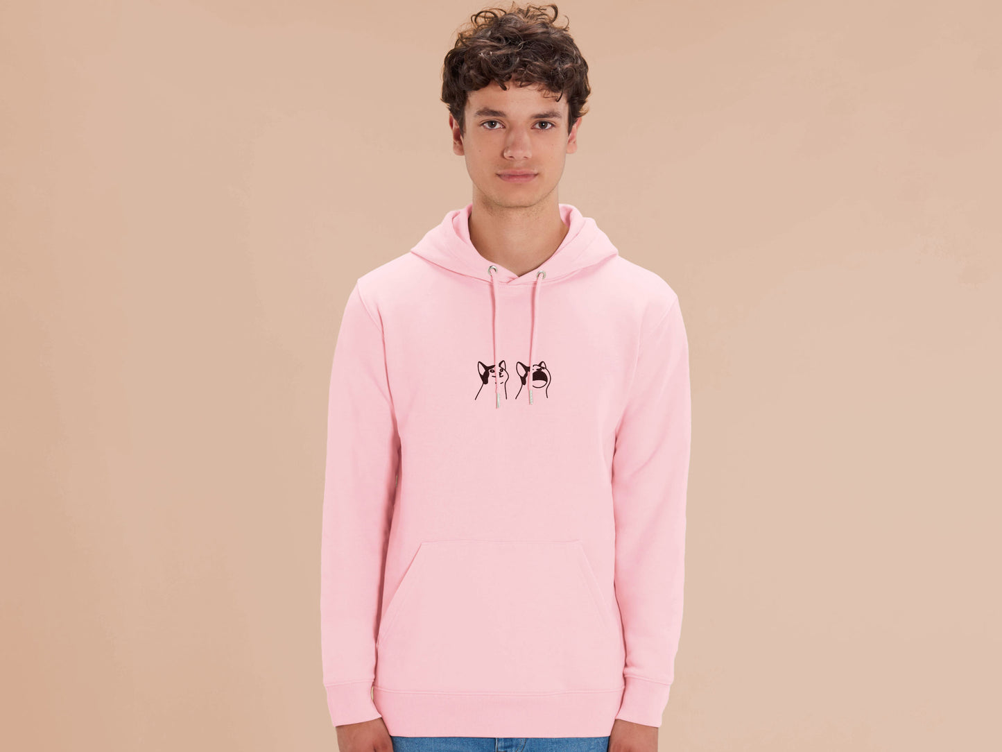 A man wearing a pink long sleeved fleece hoodie, with an embroidered brown thread design of a cute popcat the cat meme reaction twitch emote