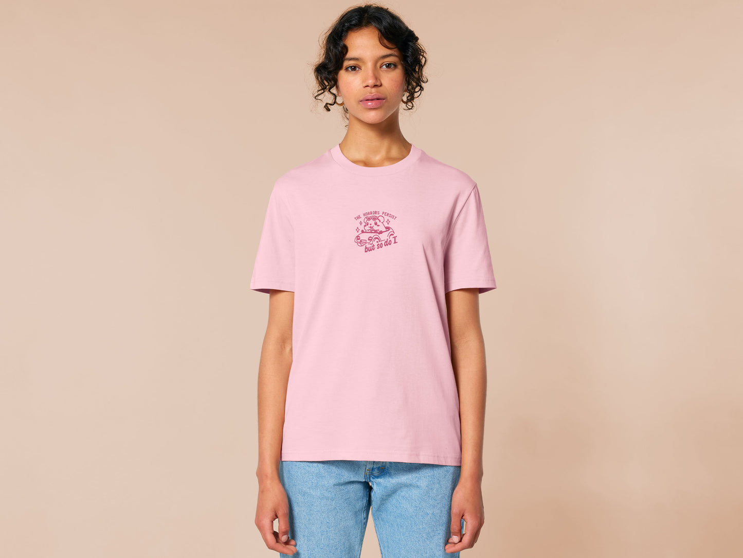 Pink embroidered t-shirt with a cute chibi guinea pig hamster wearing heart-shaped sunglasses and driving a little pink car surrounded by the quote the horrors persist but so do I.