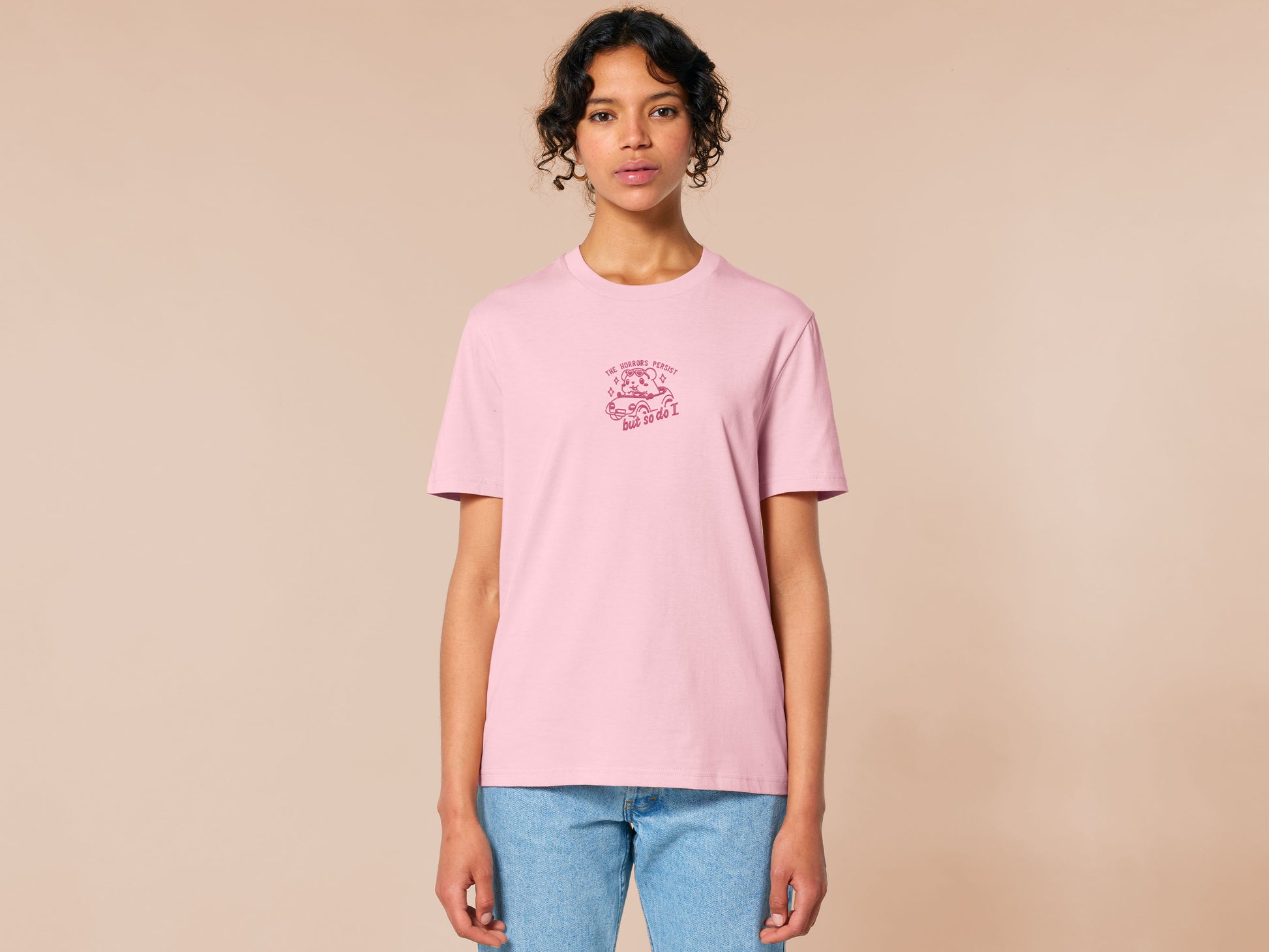 Pink embroidered t-shirt with a cute chibi guinea pig hamster wearing heart-shaped sunglasses and driving a little pink car surrounded by the quote the horrors persist but so do I.