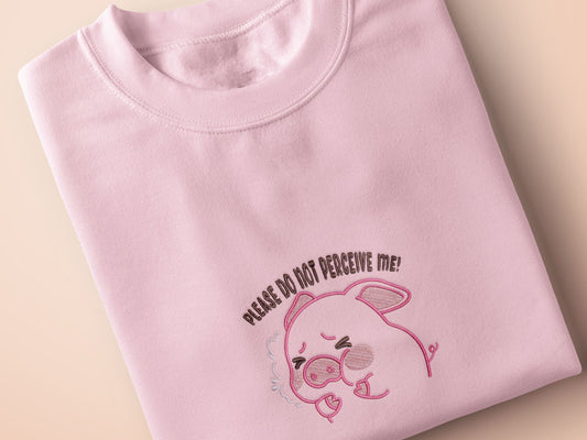 Pink embroidered t-shirt with a cute chibi panicking pig surrounded by the quote please don't perceive me