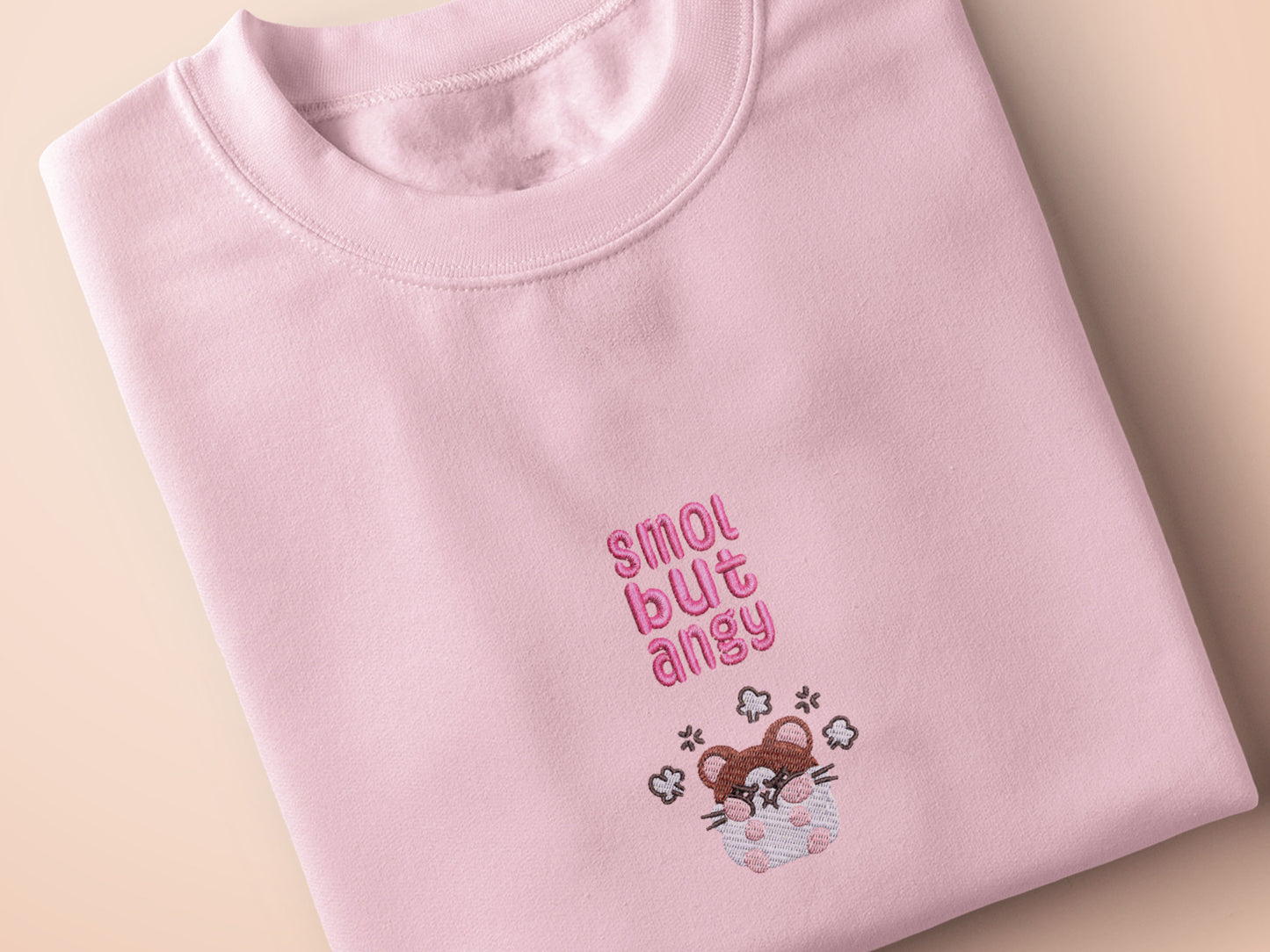 Pink embroidered t-shirt with a cute chibi hamster angry surrounded by the quote smol but angy