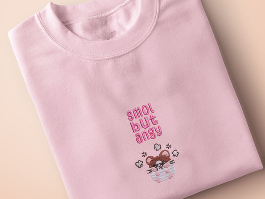 Pink embroidered t-shirt with a cute chibi hamster angry surrounded by the quote smol but angy