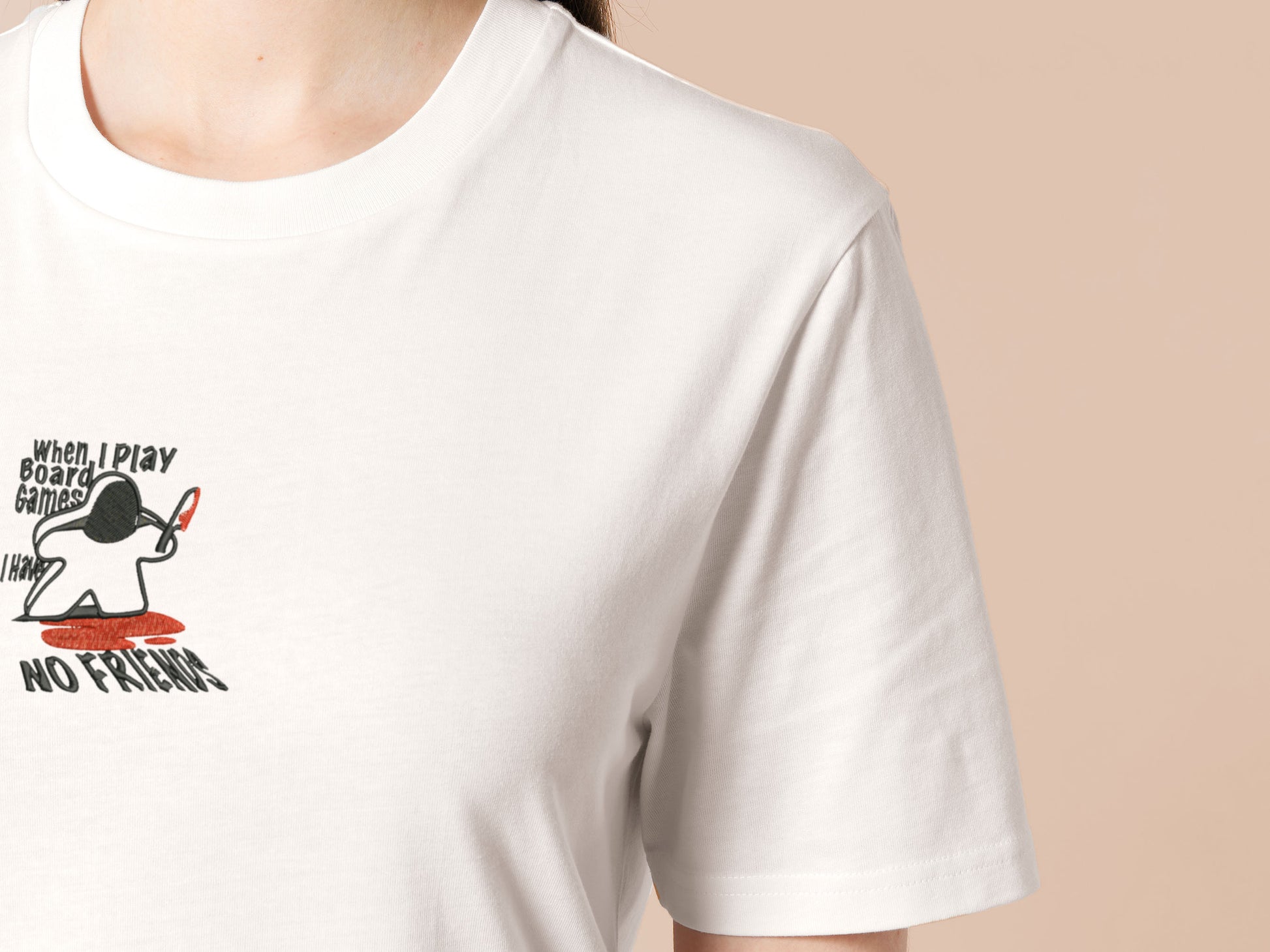 An embroidered white t-shirt design of a blood drenched meeple holding a knife with text When I Play Board Games I Have No Friends