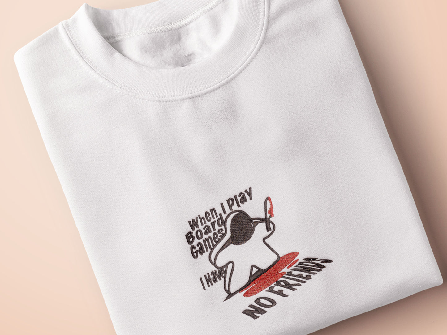 An embroidered white t-shirt design of a blood drenched meeple holding a knife with text When I Play Board Games I Have No Friends