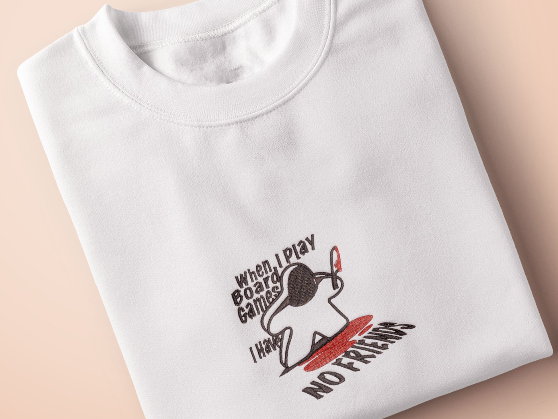 An embroidered white t-shirt design of a blood drenched meeple holding a knife with text When I Play Board Games I Have No Friends