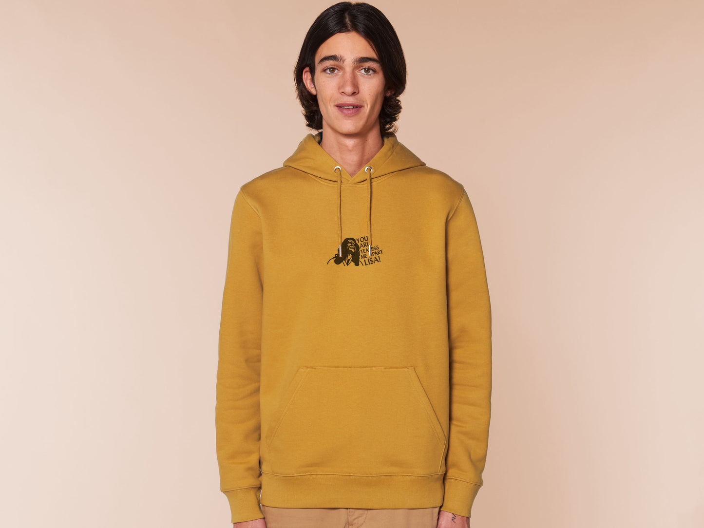 A man wearing a long sleeved yellow fleece hoodie with an embroidered black design of Tommy Wiseau in the movie The Room with the quote You Are Tearing Me Apart Lisa!
