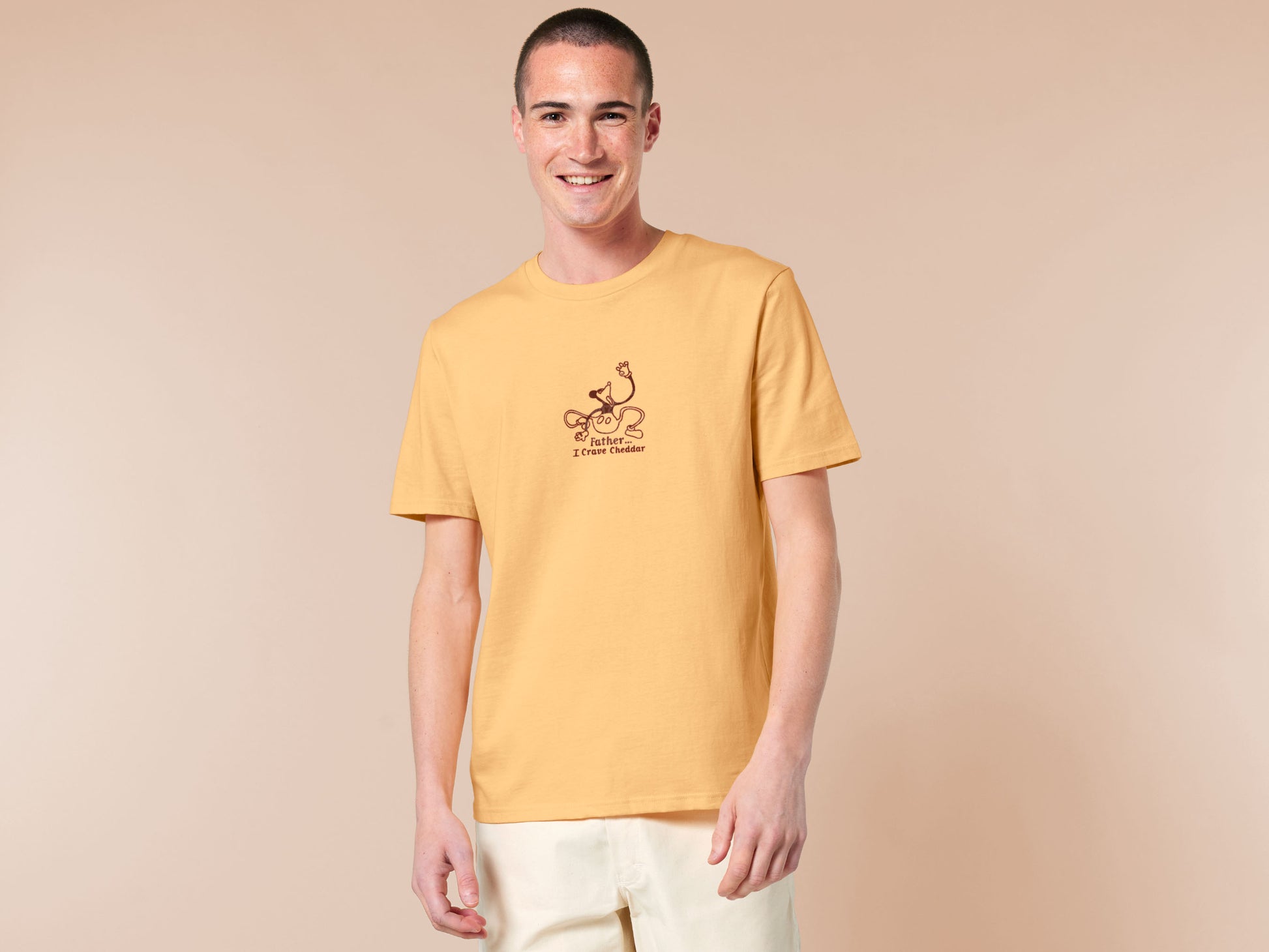 A yellow crew neck short sleeve t-shirt, with an embroidered black thread design of a mickey mouse like creature grasping the air with the text Father... I crave cheddar