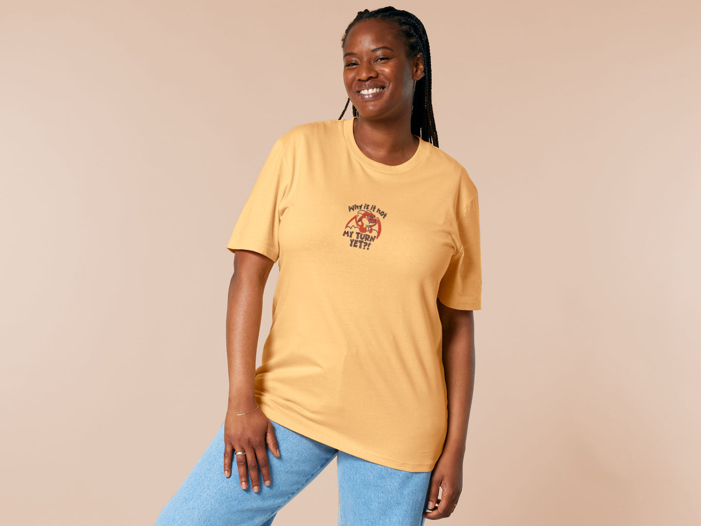 A yellow tshirt with an embroidered design of a cute grumpy red dragon playing a card game with the text why is it not my turn yet?!