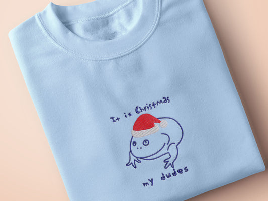 Blue Christmas jumper with an embroidered design of the viral frog Reddit meme it is Wednesday my dudes, but instead it says it is Christmas my dudes and the frog is wearing a red Christmas hat.