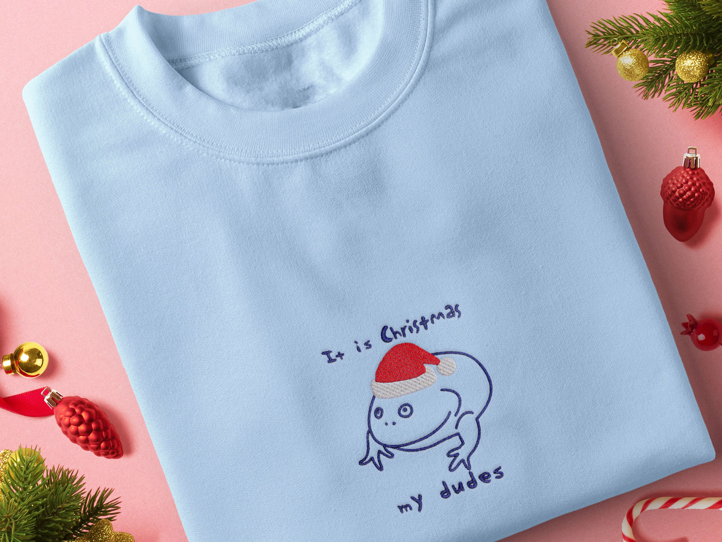 Blue Christmas jumper with an embroidered design of the viral frog Reddit meme it is Wednesday my dudes, but instead it says it is Christmas my dudes and the frog is wearing a red Christmas hat.