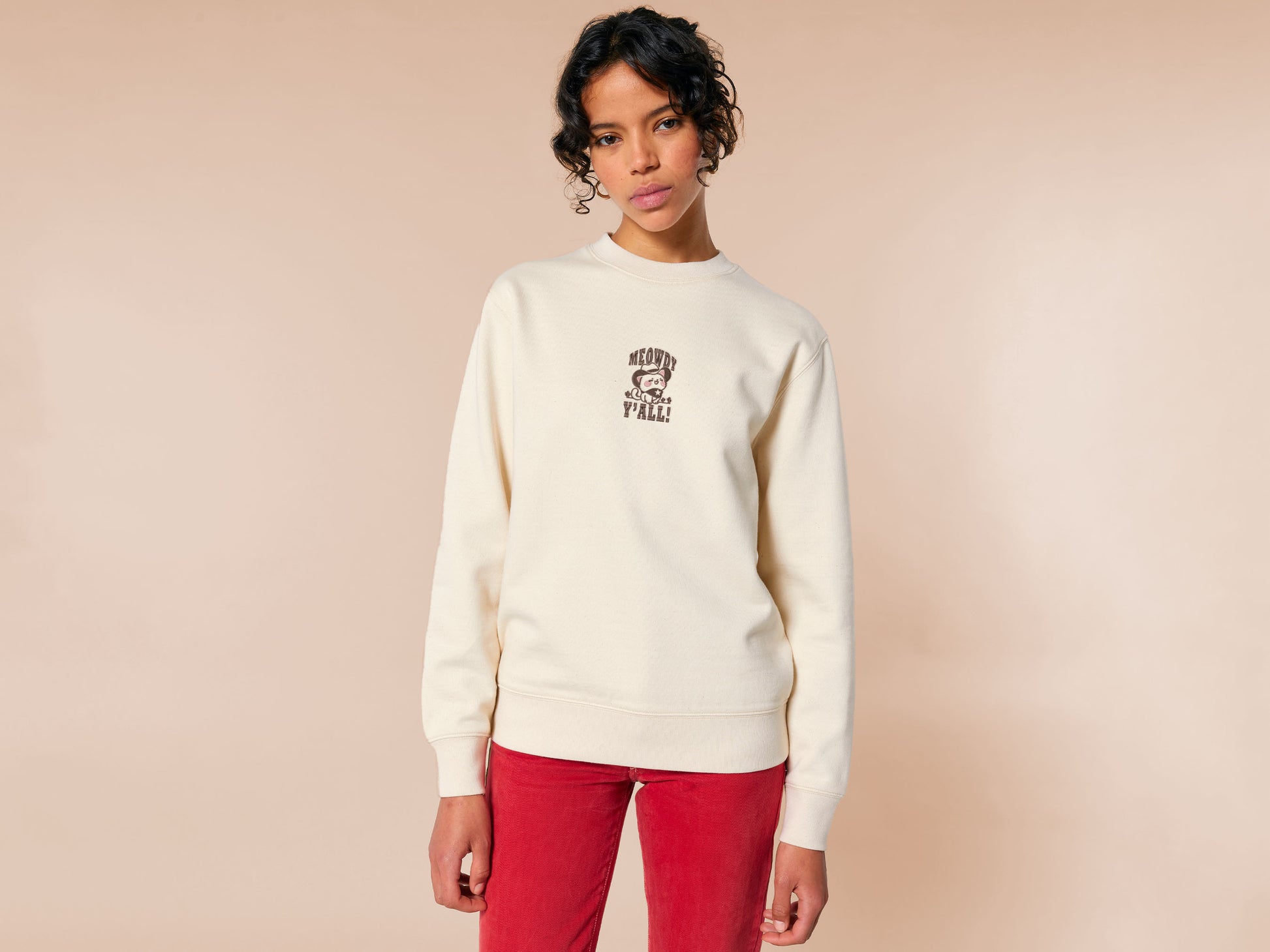A cream crew neck long sleeve sweater, with an embroidered brown thread design of a cute cowboy cat with hat surrounded by the quote meowfy ya'll!