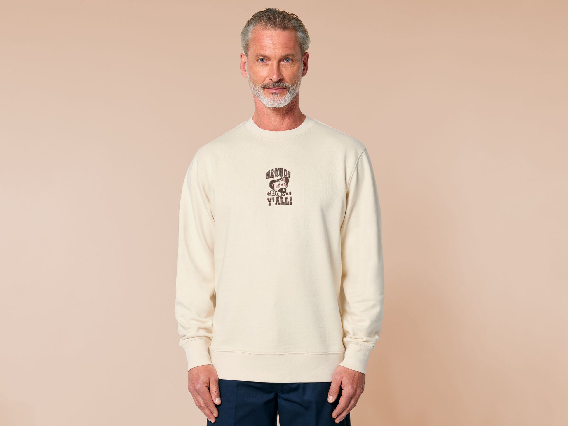 A cream crew neck long sleeve sweater, with an embroidered brown thread design of a cute cowboy cat with hat surrounded by the quote meowfy ya'll!