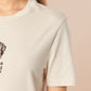 A cream crew neck short sleeve t-shirt, with an embroidered brown thread design of a cute cowboy cat with hat surrounded by the quote meowfy ya'll!