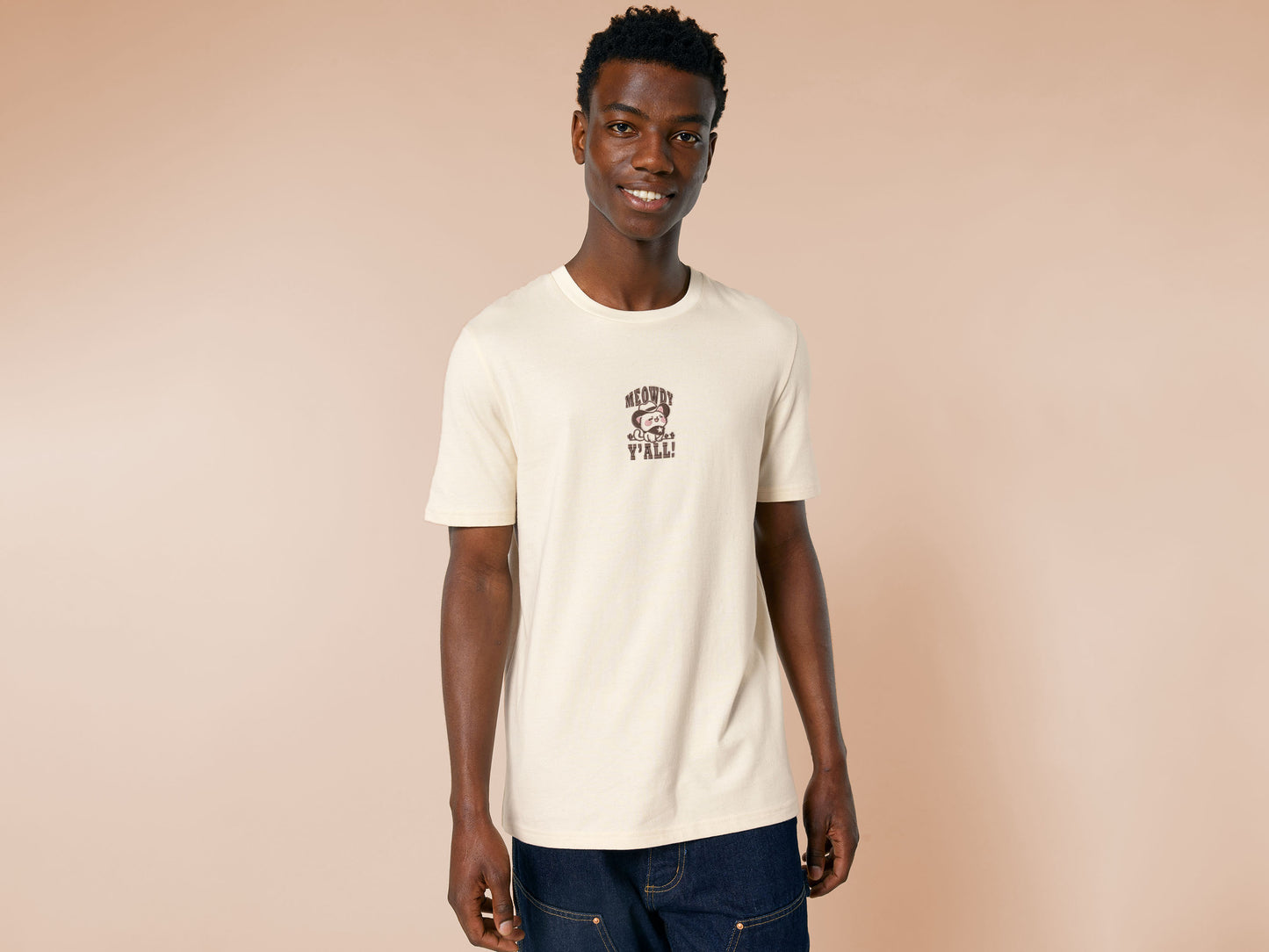 A cream crew neck short sleeve t-shirt, with an embroidered brown thread design of a cute cowboy cat with hat surrounded by the quote meowfy ya'll!