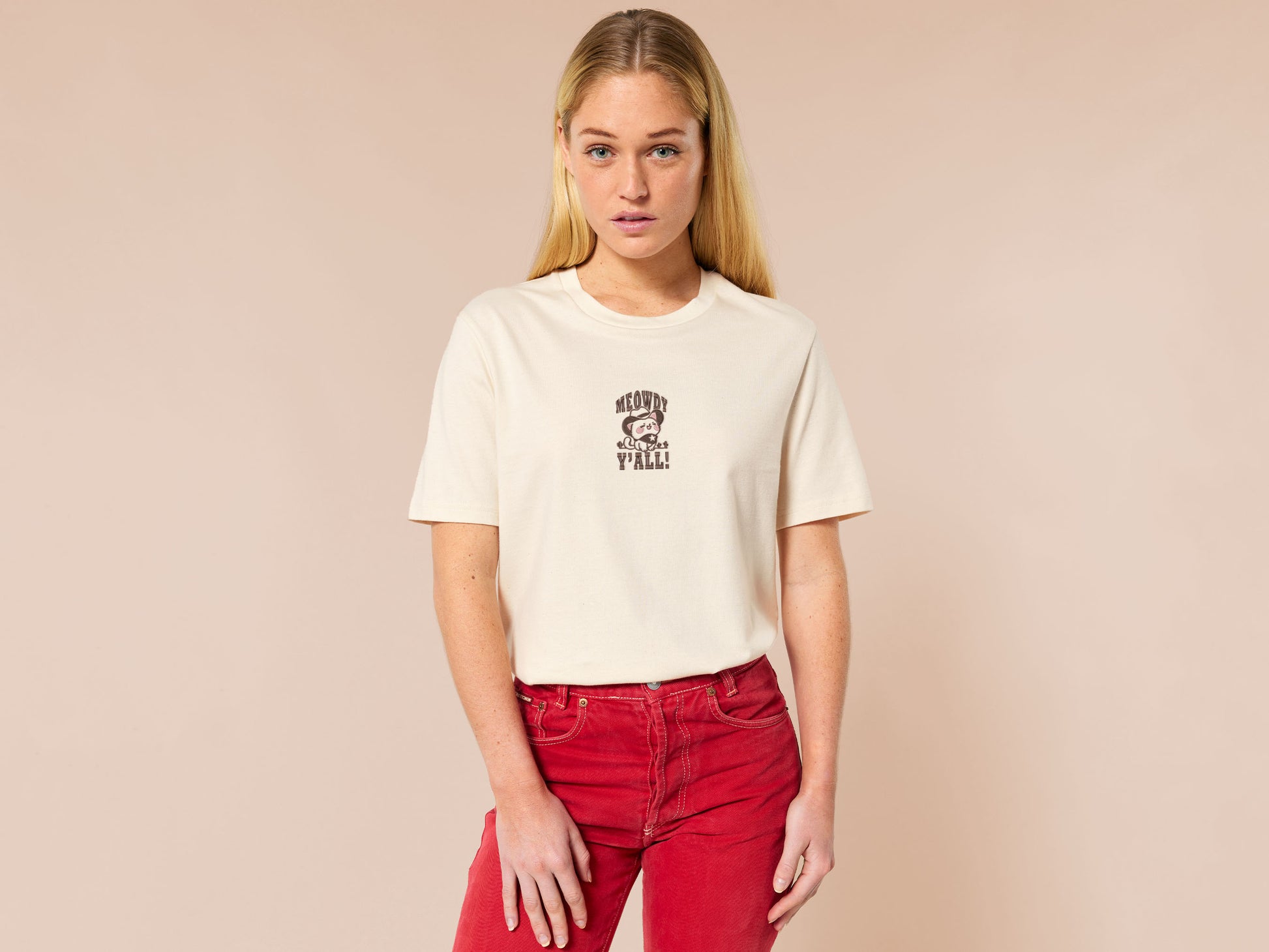 A cream crew neck short sleeve t-shirt, with an embroidered brown thread design of a cute cowboy cat with hat surrounded by the quote meowfy ya'll!