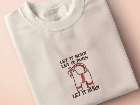 Cream Christmas jumper with an embroidered design of the viral Gavle Straw Goat surrounded by the quote let it burn, let it burn, let it burn.