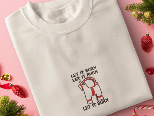Cream Christmas jumper with an embroidered design of the viral Gavle Straw Goat surrounded by the quote let it burn, let it burn, let it burn.