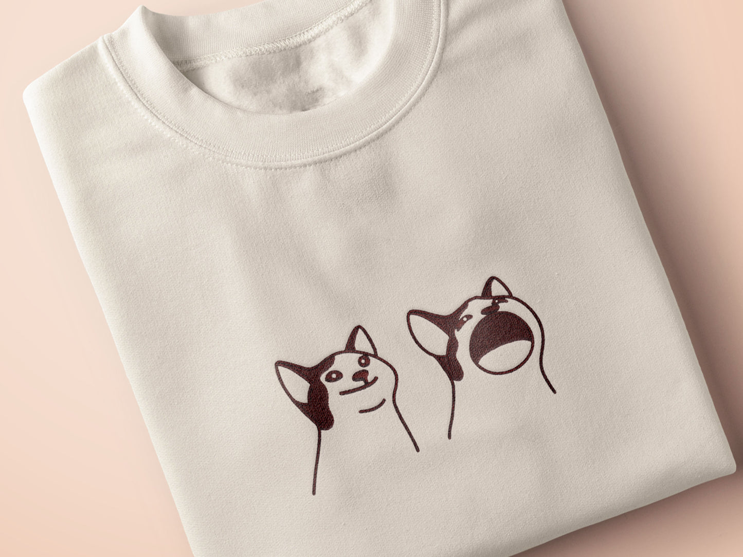 A cream crew neck short sleeve t-shirt, with an embroidered brown thread design of a cute popcat the cat meme reaction twitch emote