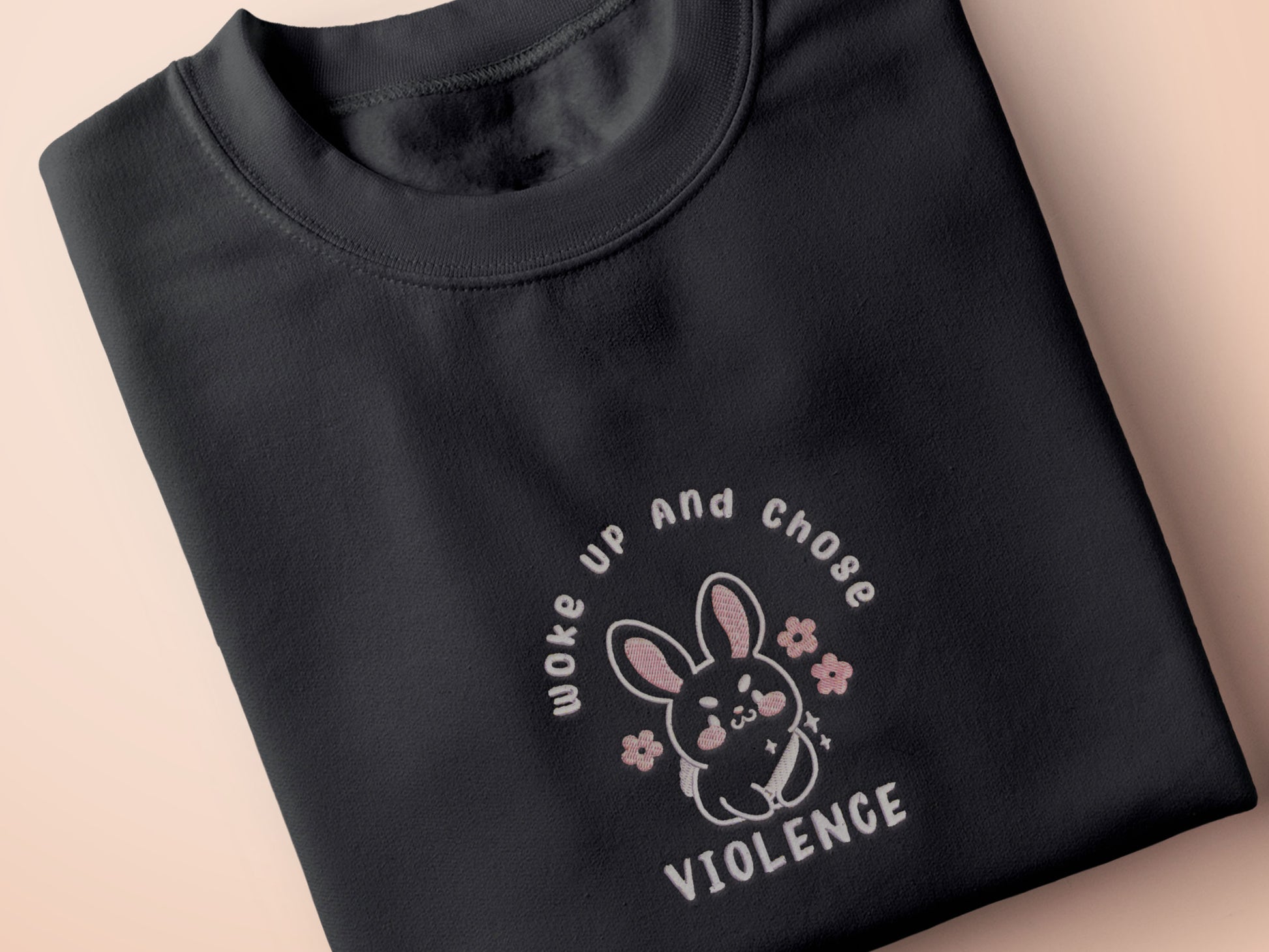 An embroidered dark grey t-shirt with a cute chibi bunny and the text Woke Up And Chose Violence.