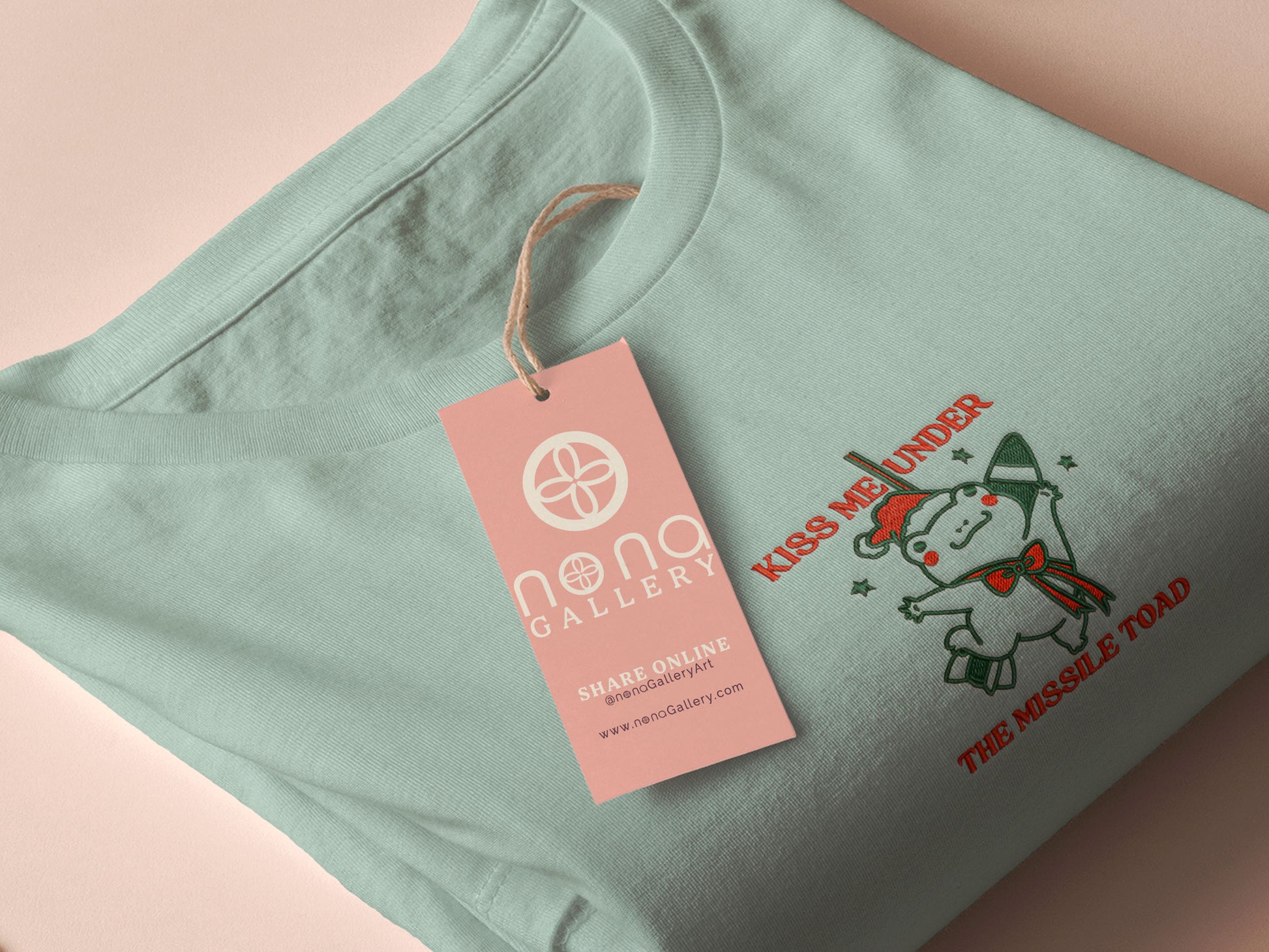 Green Christmas jumper with an embroidered design of the viral frog
meme Missile Toad, featuring a cute hanging chibi Christmas frog with the quote kiss me under the missile toad