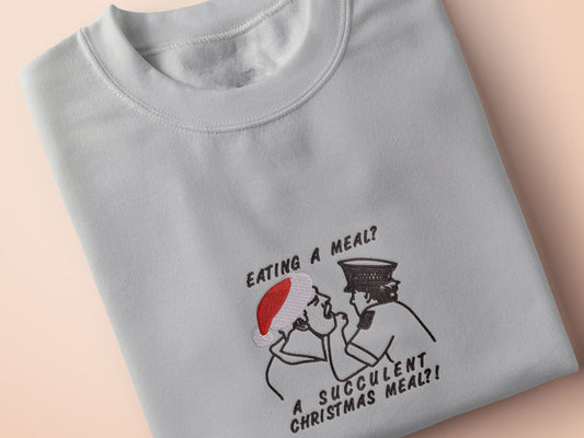 Grey Christmas jumper with an embroidered design of the viral YouTube arrest video Democracy manifest eating a meal a succulent Chinese meal, but instead, it says Christmas Meal and Jack Karlson is wearing a red Christmas hat.