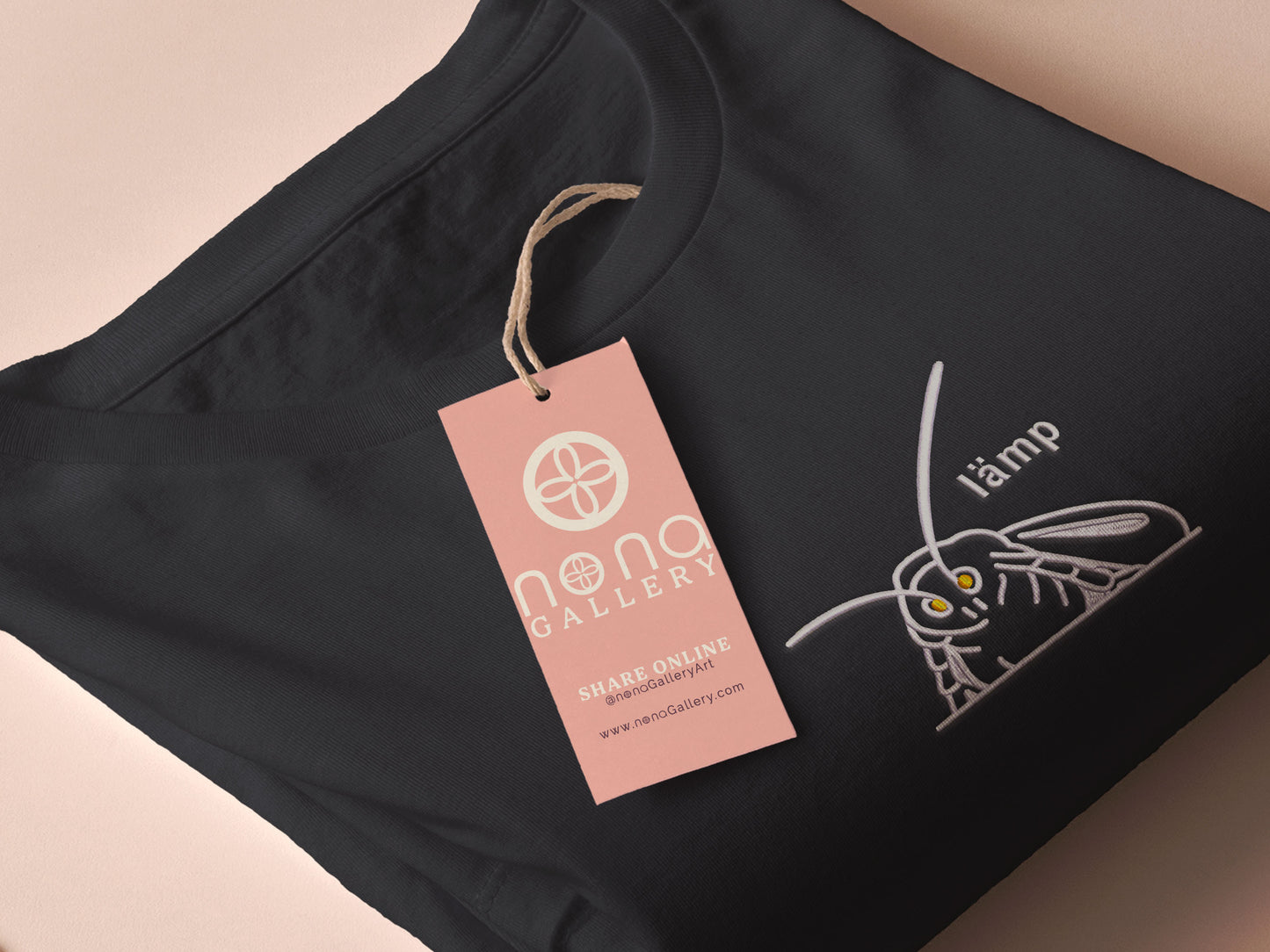 A grey crew neck short sleeve t-shirt, with an embroidered Mothman white thread design of a moth with glowing yellow eyes and the word lämp