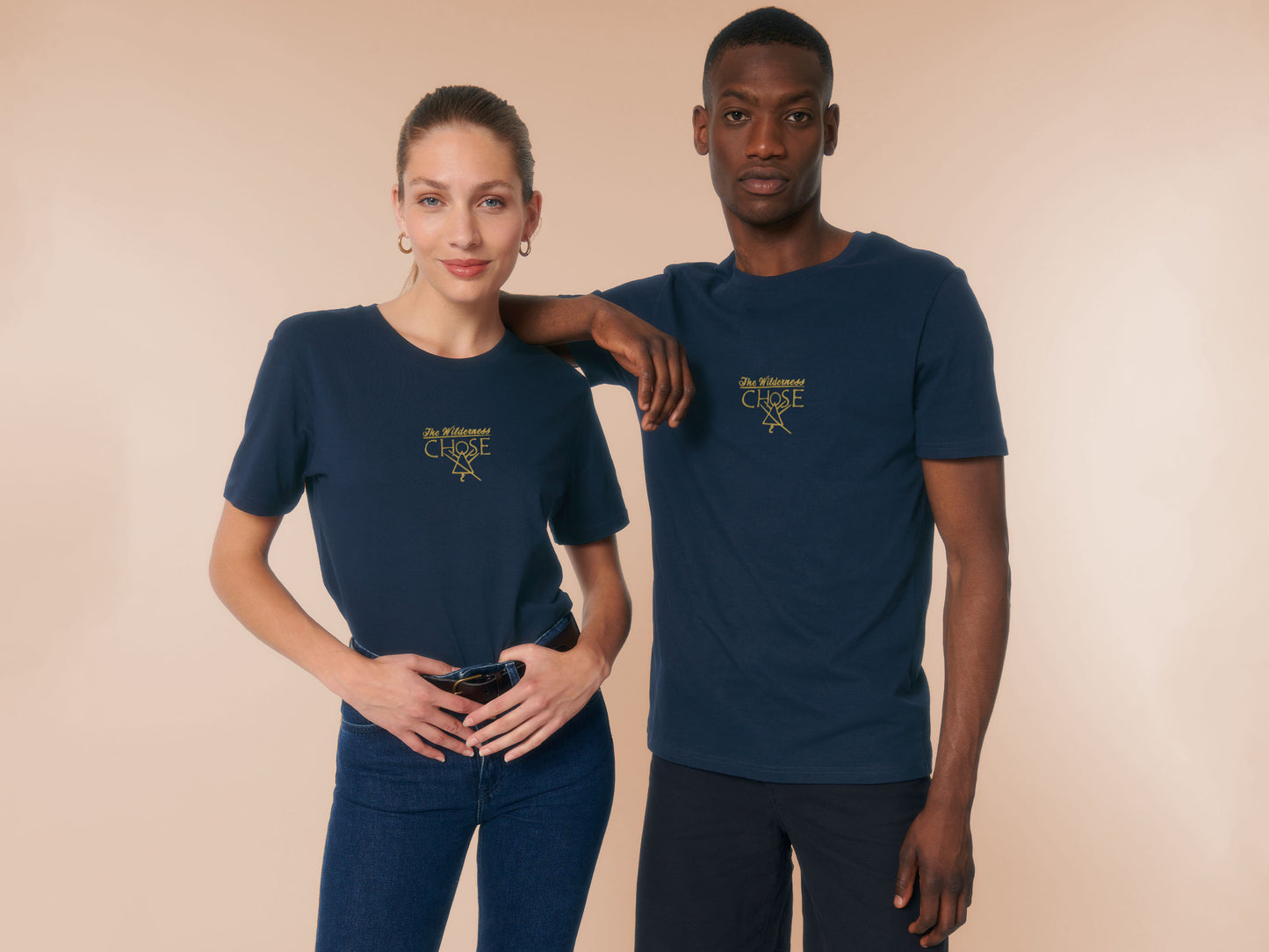 An embroidered yellow design on a navy t-shirt with the quote The Wilderness chose, featuring the cult symbol from the TV show Yellowjackets
