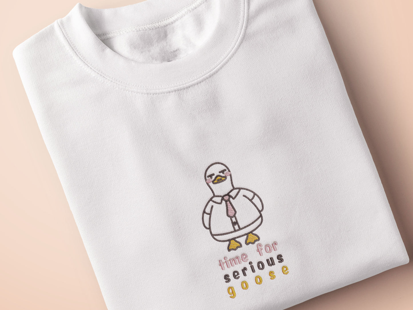 An embroidered white t-shirt design of a cute cartoon goose wearing a suit and tie with text underneath that time for serious goose