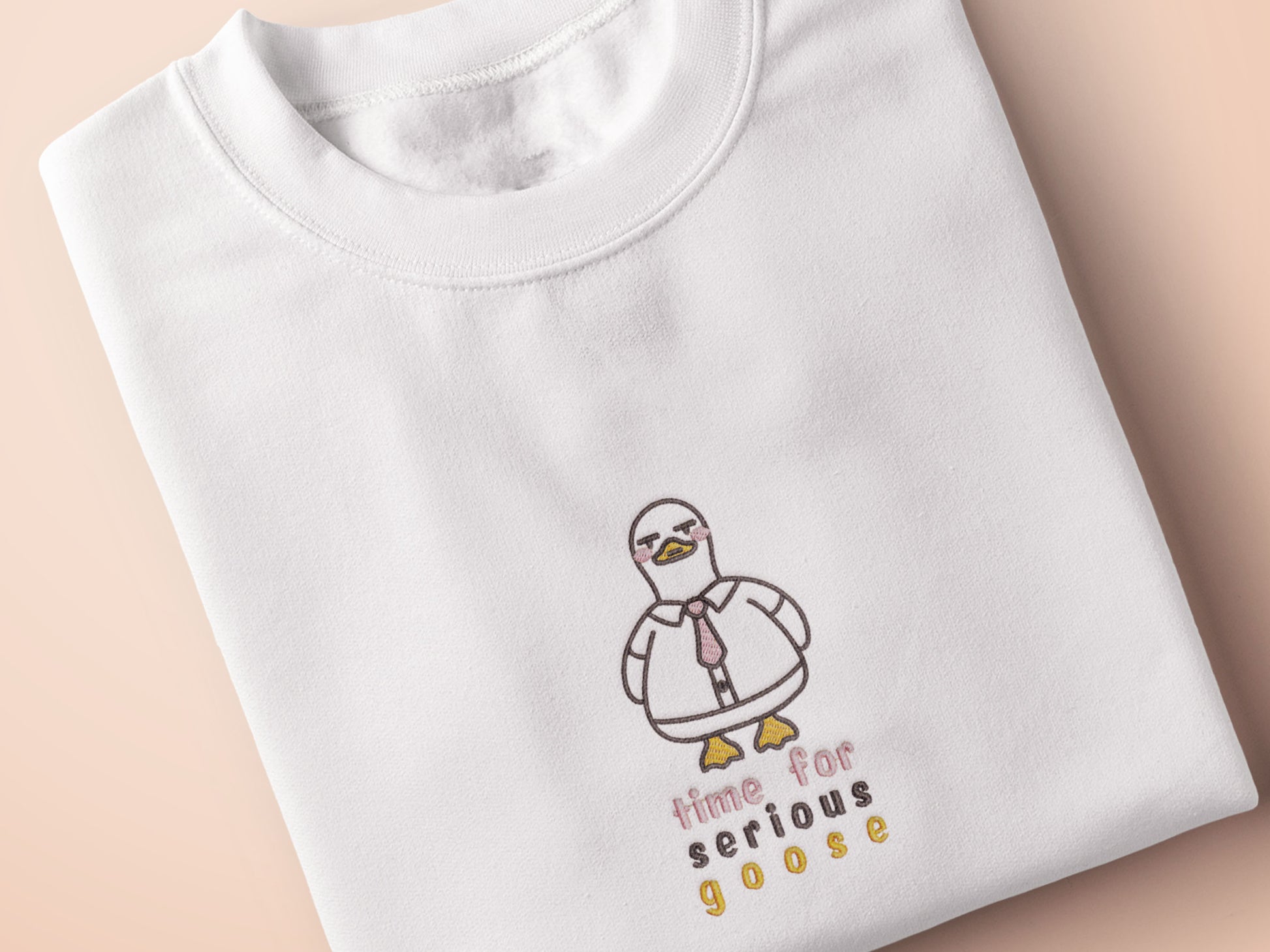 An embroidered white t-shirt design of a cute cartoon goose wearing a suit and tie with text underneath that time for serious goose