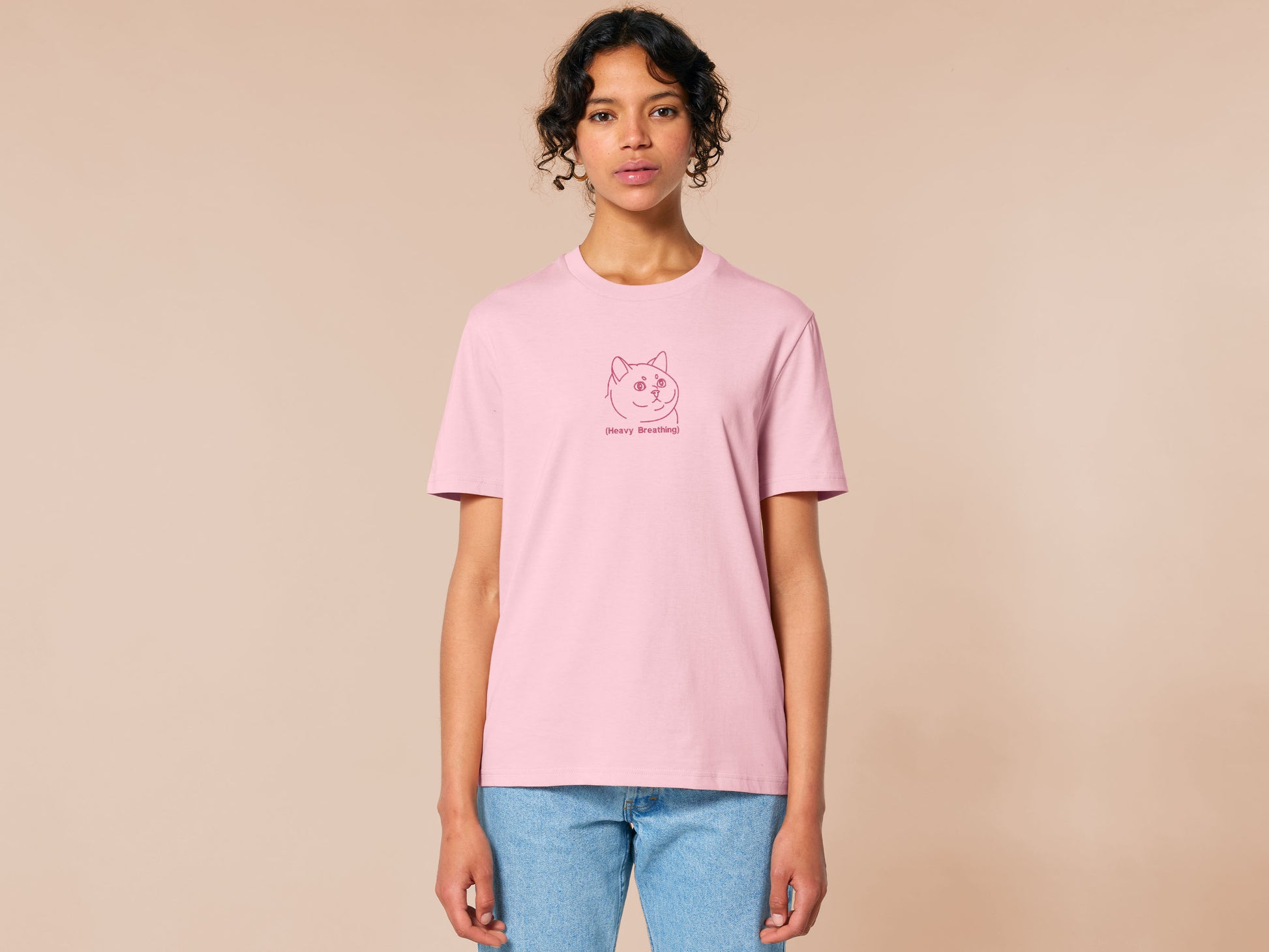 A pink crew neck short sleeve t-shirt, with an embroidered pink thread design of a cute fat cat portrait with text underneath saying (Heavy Breathing)