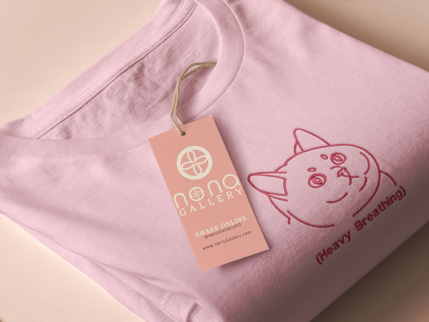 A pink crew neck short sleeve t-shirt, with an embroidered pink thread design of a cute fat cat portrait with text underneath saying (Heavy Breathing)