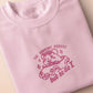 Pink embroidered t-shirt with a cute chibi guinea pig hamster wearing heart-shaped sunglasses and driving a little pink car surrounded by the quote the horrors persist but so do I.