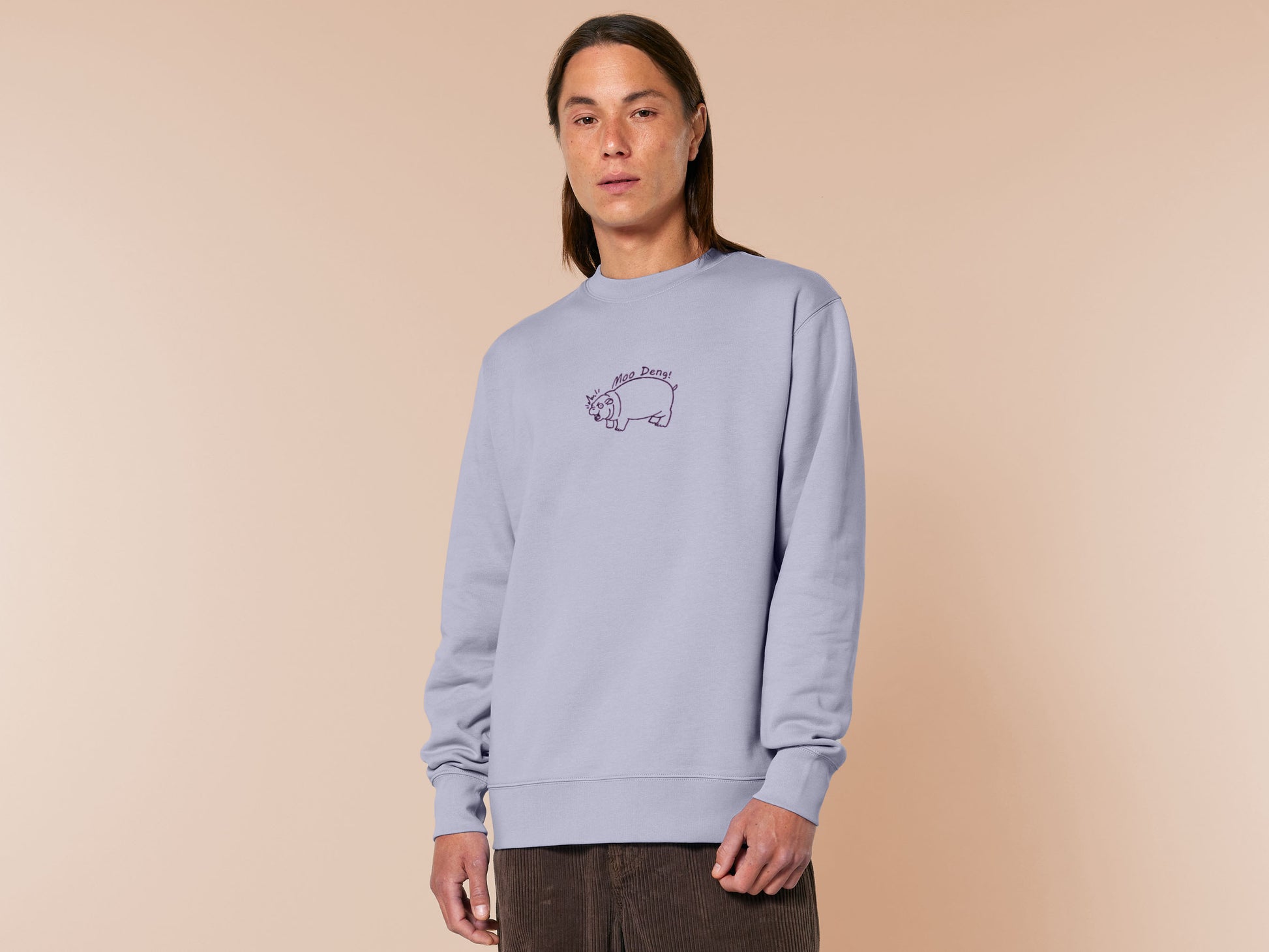 A purple sweater with an embroidered design of a cute chibi illustration of the viral baby pygmy hippo looking shocked with the quote Moo Deng!