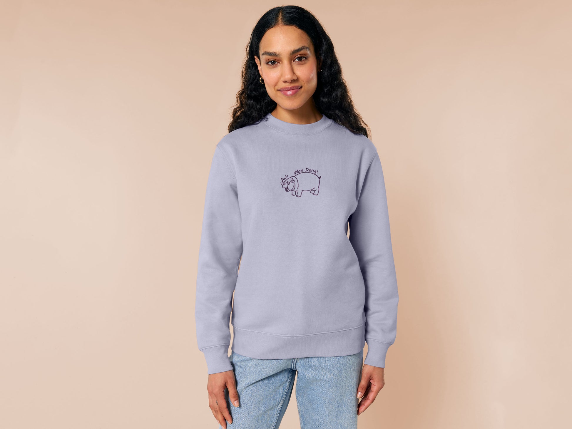 A purple sweater with an embroidered design of a cute chibi illustration of the viral baby pygmy hippo looking shocked with the quote Moo Deng!