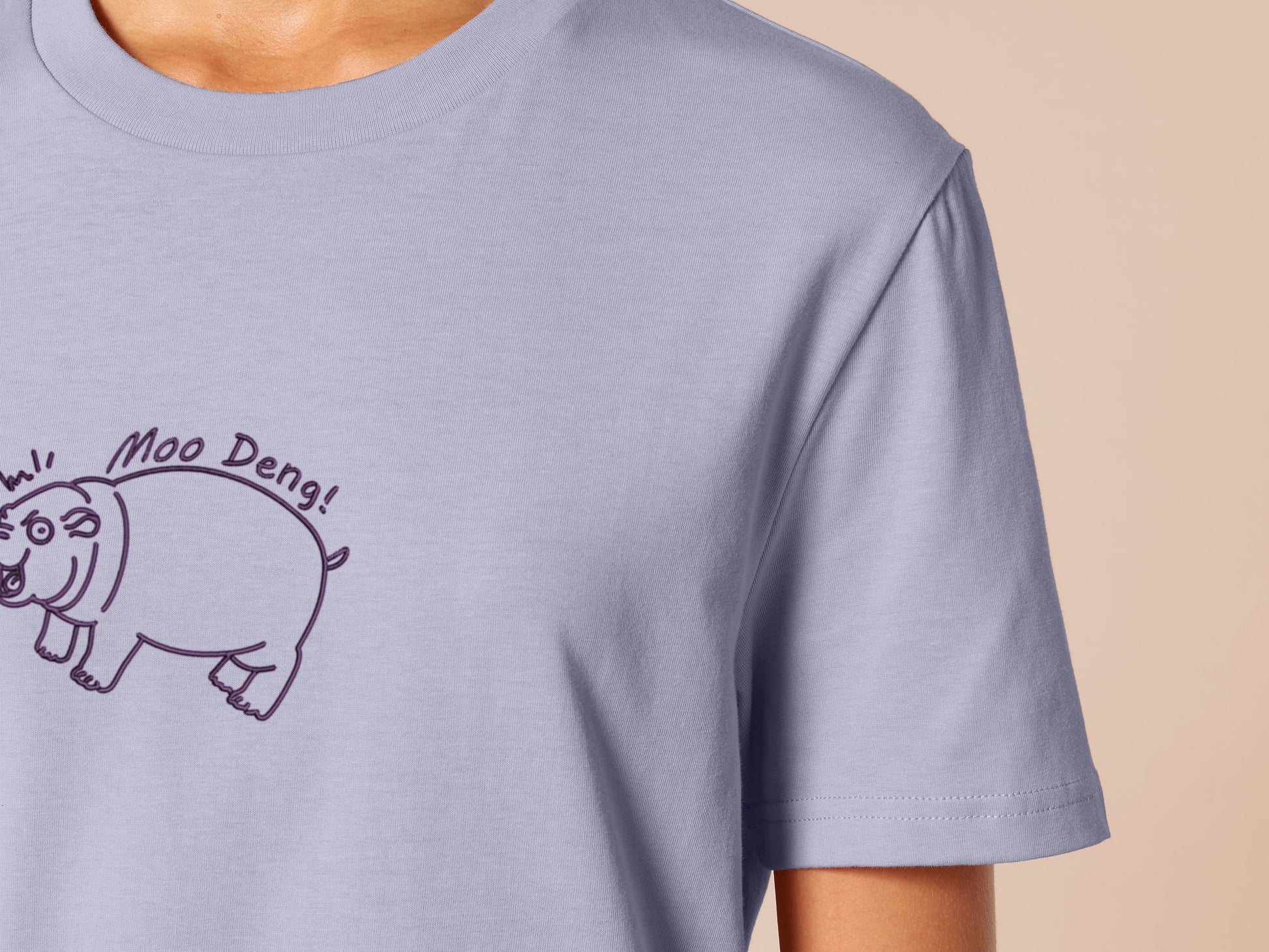 A purple t-shirt with an embroidered design of a cute chibi illustration of the viral baby pygmy hippo looking shocked with the quote Moo Deng!