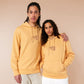 A yellow crew neck long sleeve hoodie, with an embroidered brown thread design of a cute singing cat wearing a cowboy hat and the song lyric country roads, take me home to the place I belong