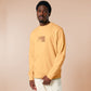 A yellow crew neck long sleeve sweater, with an embroidered brown thread design of a cute singing cat wearing a cowboy hat and the song lyric country roads, take me home to the place I belong