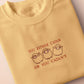 A yellow top with a brown and red embroidered design of cute chibi sheep with the text you either catan or you catan't
