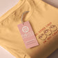 A yellow top with a brown and red embroidered design of cute chibi sheep with the text you either catan or you catan't