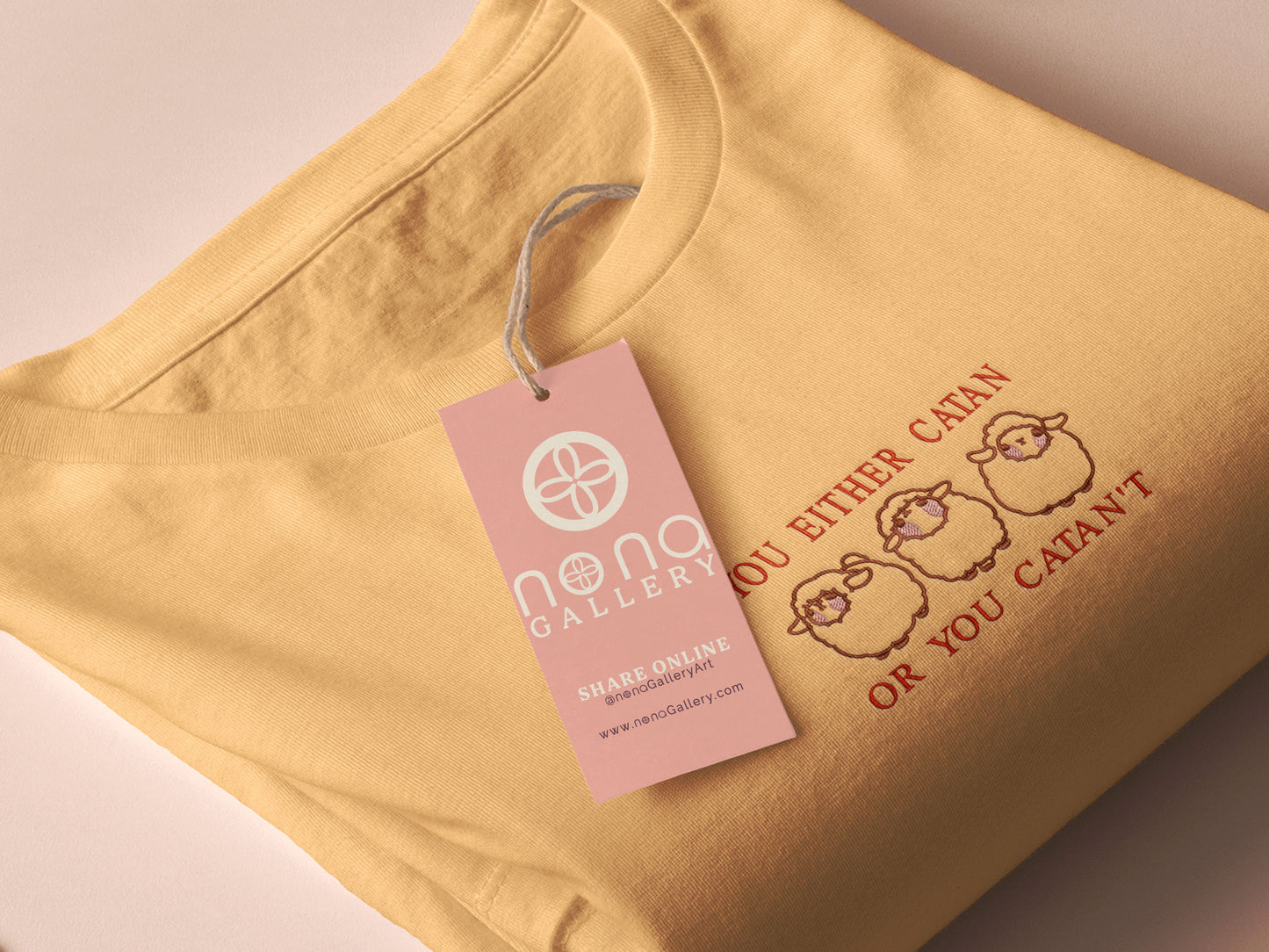 A yellow top with a brown and red embroidered design of cute chibi sheep with the text you either catan or you catan't
