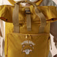 Yellow roll top twin handle backpack with an embroided design of cute crying bear and the quote emotional baggage