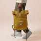 Yellow roll top twin handle backpack with an embroided design of cute crying bear and the quote emotional baggage