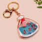 A large transparent acrylic shaker keychain with gold keyring, filled with mini chibi shrimps and labelled as emotional support shrimp