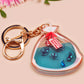 A large transparent acrylic shaker keychain with gold keyring, filled with mini chibi shrimps and labelled as emotional support shrimp